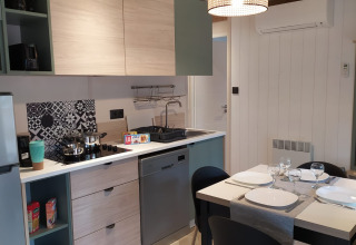 Moderne glamping indkvartering med køkken, spisebord, opvaskemaskine og minimalistisk indretning.