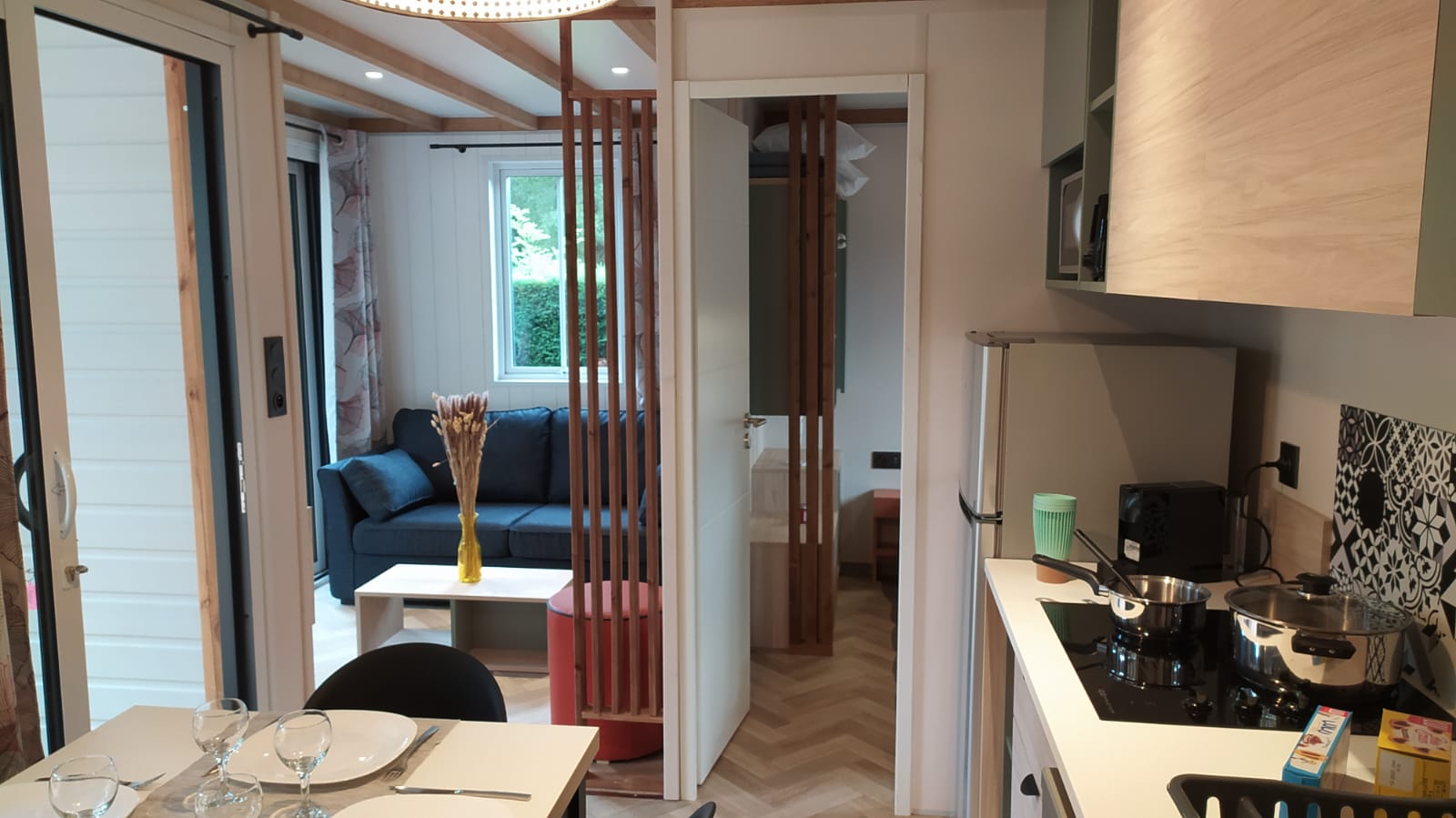 Moderne glampingaccommodatie met complete keuken, eethoek en knusse zithoek in een natuurlijke setting.