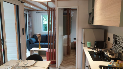 Moderne glampingverblijf met uitgeruste keuken, eetruimte en een gezellige zithoek in een groene omgeving.