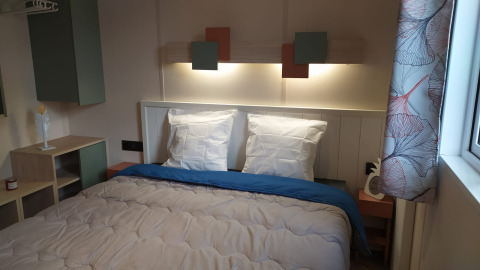 Camera glamping moderna con letto matrimoniale, luci a parete soffuse e tende con motivi eleganti.