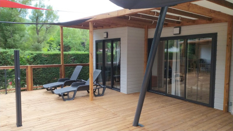 Houten terras met ligstoelen bij Chalet Tribu Premium op Flower Camping La Rivière in Frankrijk.