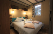 Dormitorio en Chalet Tribu Premium de Flower Camping La Rivière, con cama doble y bandeja de desayuno.
