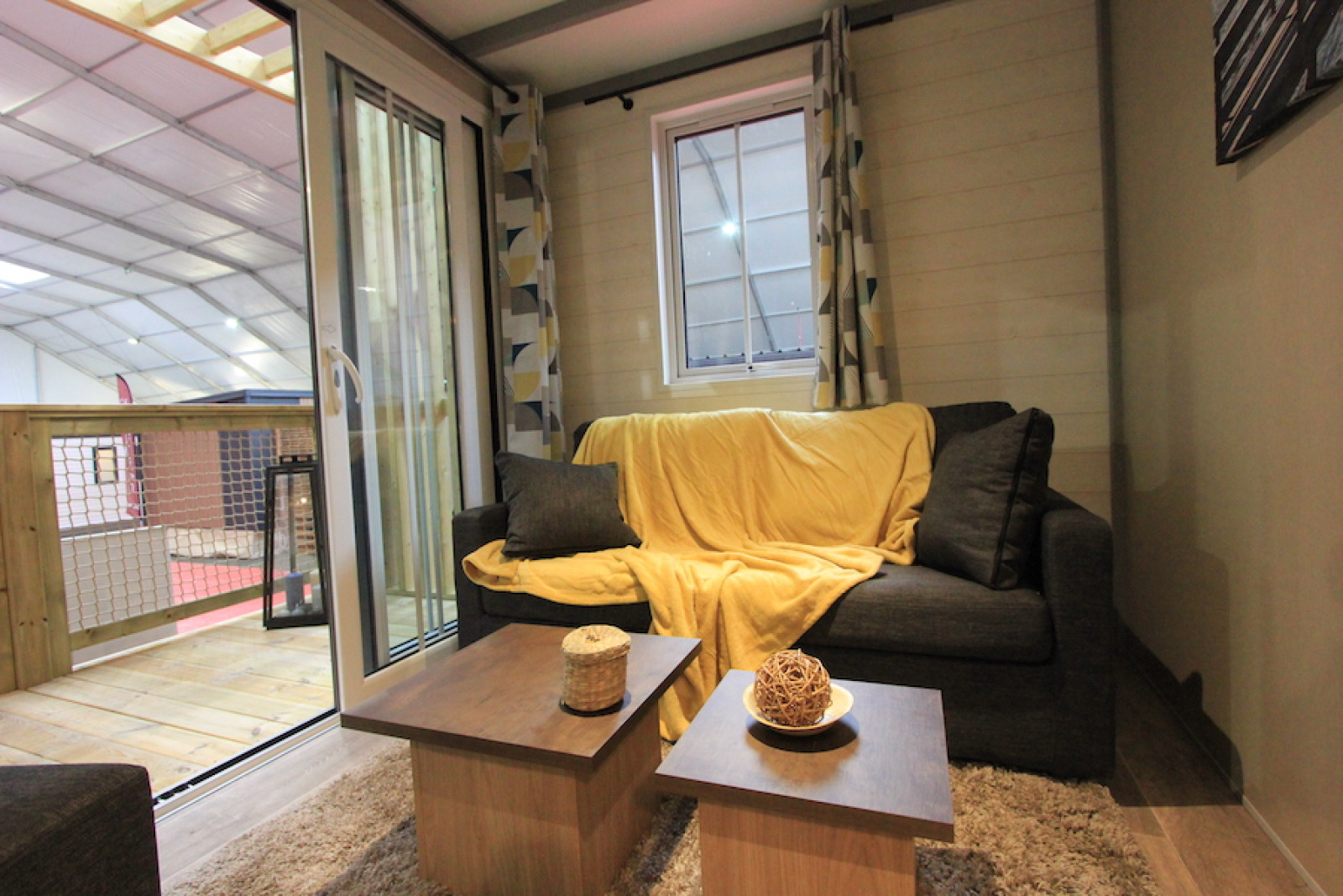 Woonruimte in Chalet Tribu Premium, Flower Camping La Rivière, Frankrijk met bank en balkon.