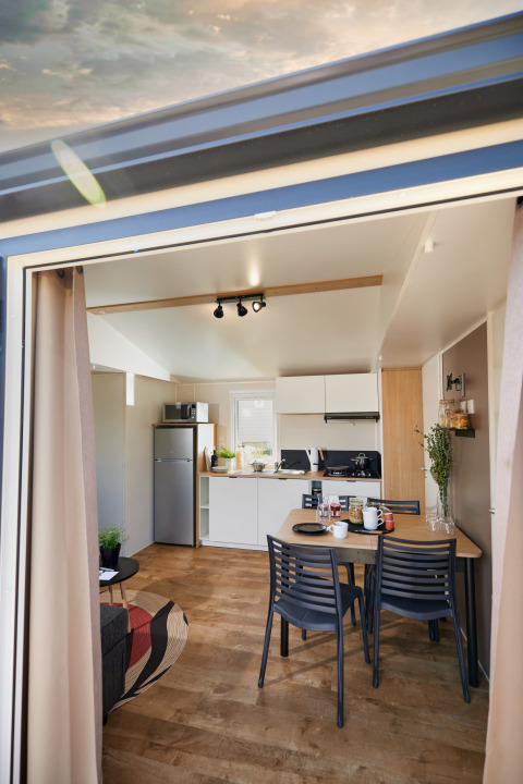 Foto van een glamping accommodatie met moderne keuken, eettafel op houten vloer en open inkom.