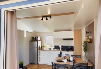 Photo of a modern glamping kitchen and dining area with wooden floors, open entrance, and cozy decor.
