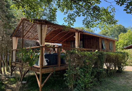 Cabaña Charme con jacuzzi, casa de madera rústica con terraza cubierta rodeada de vegetación.