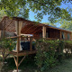 Cabane Charme avec jacuzzi, chalet en bois rustique avec terrasse couverte entourée de verdure.