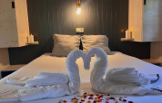 Letto romantico con cigni di asciugamani, candele e petali di rosa nella Charme hut con jacuzzi, Camping Le Périgord.