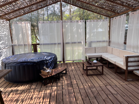 Terrasse extérieure avec jacuzzi à Charme hut met jacuzzi, Camping Le Périgord, France. Salon en bois.