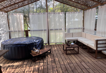 Outdoor deck at Charme hut met jacuzzi, Camping Le Périgord, France. Hot tub and wood seating area.