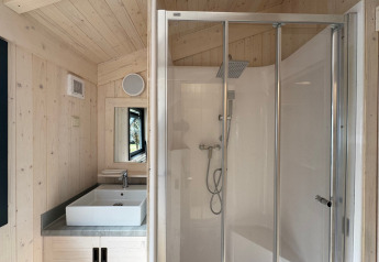 Bathroom inside Charme hut with jacuzzi at Camping Le Périgord, France, featuring shower and sink area.