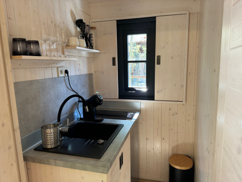 Kleine kitchenette in Charme hut met jacuzzi op Camping Le Périgord, voorzien van gootsteen en raam.