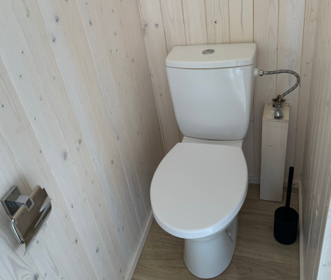Moderno WC bianco con pareti e pavimento in legno nella Charme hut met jacuzzi, Camping Le Périgord, Francia.