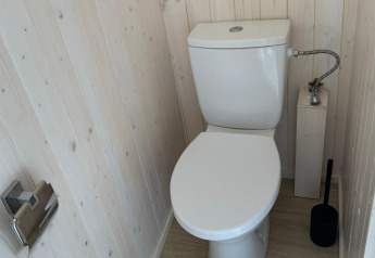 Inodoro blanco moderno con paredes y suelo de madera en Charme hut met jacuzzi, Camping Le Périgord, Francia.