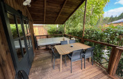 Overdekt houten terras van de Premium Hut op Camping Le Périgord, Frankrijk, met tafel en stoelen buiten.