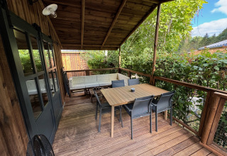 Terrasse en bois couverte à la Premium Hut du Camping Le Périgord, France, aménagée avec table et chaises.