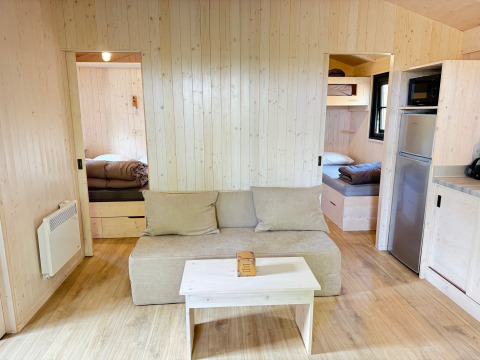 Vue intérieure de la Premium Hut au Camping Le Périgord en France, décorée de bois clair et mobilier confortable.