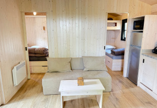 Vista interna della Premium Hut al Camping Le Périgord in Francia, con pareti in legno e arredi accoglienti.