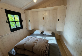 Camera Premium Hut con letto matrimoniale e pareti in legno al Camping Le Périgord, Francia.