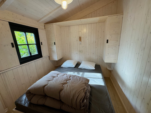 Dormitorio de Premium Hut con cama doble y paredes de madera en Camping Le Périgord, Francia.