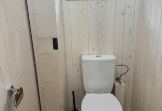 Bagno moderno nella Premium Hut al Camping Le Périgord, Francia, con pareti in legno chiaro e finestra.