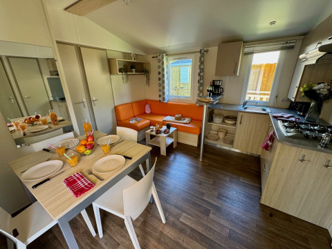 Interni moderni del Comfort Cottage al Camping Le Périgord in Francia, con zona pranzo e divano angolare.
