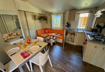 Modern interieur van Comfort Cottage op Camping Le Périgord in Frankrijk, met eethoek en zithoek.
