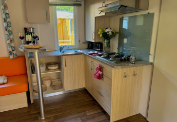 Gezellige keuken in Comfort Cottage op Camping Le Périgord, Frankrijk met wijn, brood en bloemen.