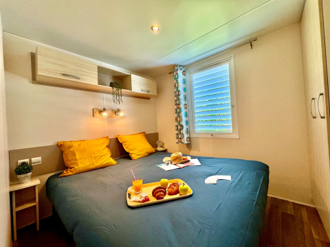 Acogedor dormitorio en Comfort Cottage de Camping Le Périgord, Francia, con desayuno servido en la cama.