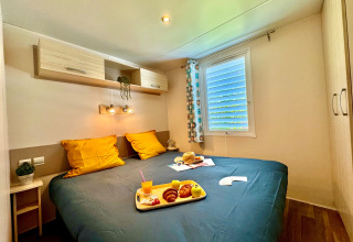 Acogedor dormitorio en Comfort Cottage de Camping Le Périgord, Francia, con desayuno servido en la cama.