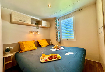 Komfortabelt soveværelse i Comfort Cottage på Camping Le Périgord, Frankrig med morgenmad på sengen.