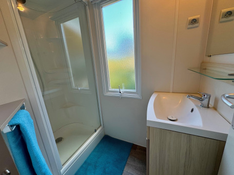 Baño moderno en Comfort Cottage de Camping Le Périgord, con ducha, lavabo y gran ventana.