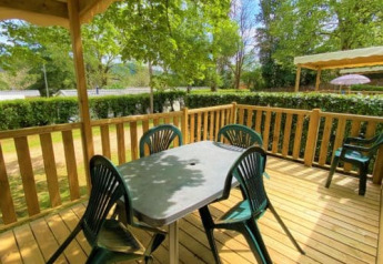Udendørs træterrasse ved Classic Cottage på Camping Le Périgord i Frankrig med plastbord og stole.