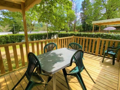 Terrazza in legno all'aperto con tavolo e sedie del Classic Cottage presso Camping Le Périgord, Francia.