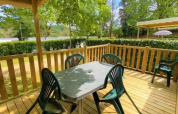 Terrazza in legno all'aperto con tavolo e sedie del Classic Cottage presso Camping Le Périgord, Francia.
