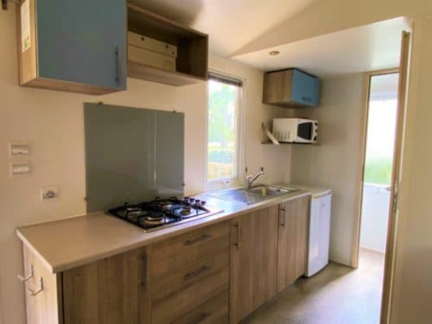 Cocina luminosa en Classic Cottage del Camping Le Périgord, Francia, con estufa, fregadero y armarios.