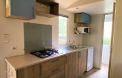 Lichte keuken in Classic Cottage op Camping Le Périgord, Frankrijk, met fornuis, gootsteen en kasten.