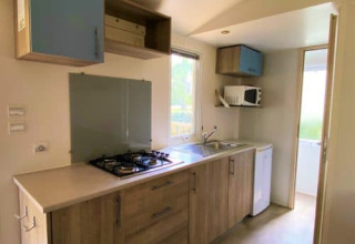 Cocina luminosa en Classic Cottage del Camping Le Périgord, Francia, con estufa, fregadero y armarios.