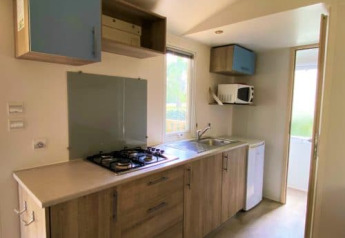 Cucina luminosa nel Classic Cottage al Camping Le Périgord in Francia, con fornello, lavello e mobili.