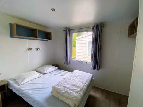 Camera da letto con letto matrimoniale, finestra e arredo semplice in Classic Cottage al Camping Le Périgord, Francia.