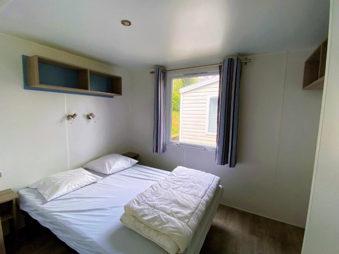 Dormitorio con cama doble, ventana y decoración sencilla en Classic Cottage en Camping Le Périgord, Francia.