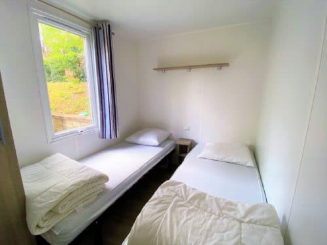 Dos camas individuales sencillas en una habitación luminosa en Classic Cottage, Camping Le Périgord, Francia.