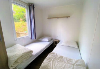 Due semplici letti singoli in una stanza luminosa nel Classic Cottage al Camping Le Périgord, Francia.