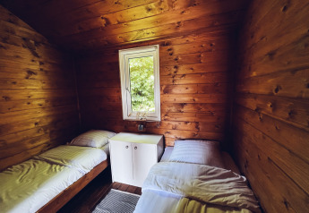 Houten blokhut met twee aparte bedden, raam met natuurzicht en eenvoudig interieur in Nederland.