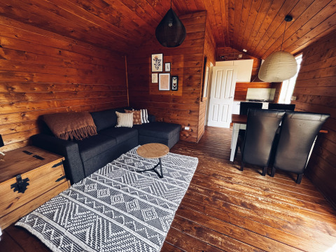 Interior de cabaña de camping en REBL Outdoor, Países Bajos, con paredes de madera y sofá negro cómodo.