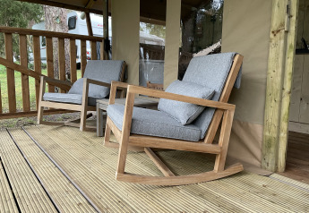Twee gezellige schommelstoelen met grijze kussens op het terras van de safaritent Summer Lodge in Beerze Bulten.