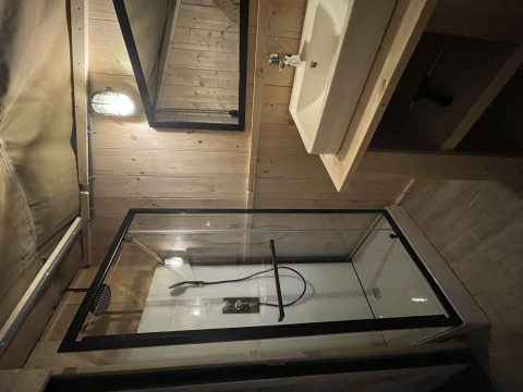 Moderne badkamer met douche, lavabo en spiegel in een safaritent in Summer Lodge, Beerze Bulten, Nederland.