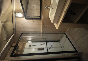 Baño moderno con ducha, lavabo y espejo en una tienda safari en Summer Lodge, Beerze Bulten, Países Bajos.