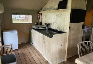 Pequeña cocina de madera en tienda safari en Summer Lodge, Beerze Bulten, Países Bajos, bien equipada.