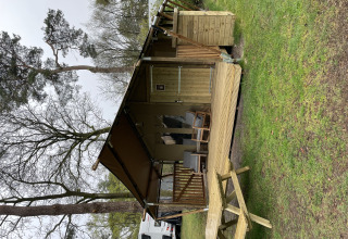 Tienda safari Summer Lodge en Beerze Bulten, Países Bajos, con terraza de madera y mesa de picnic exterior.